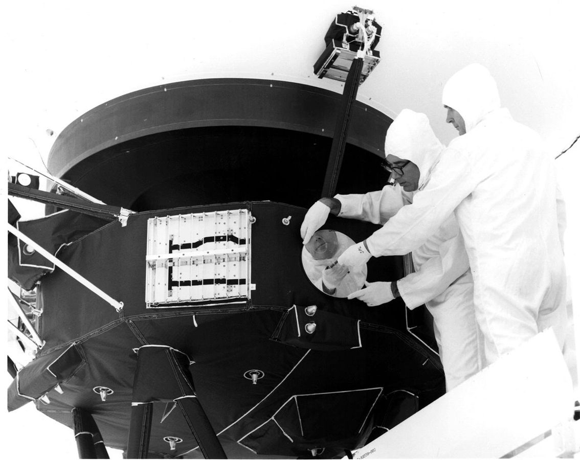 Technici upevňují ochranný kryt desky na Voyager 1 v roce 1977.
